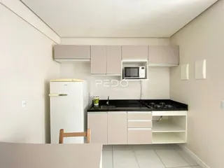 Cozinha moderna com armários brancos e bancada escura.