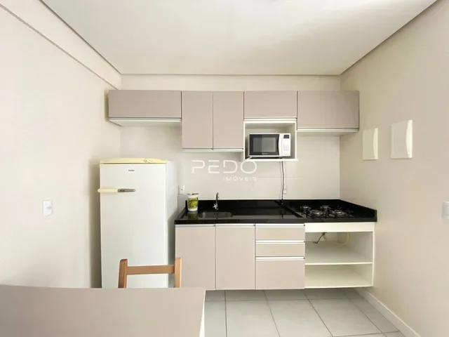 Cozinha moderna com armários brancos e bancada escura.