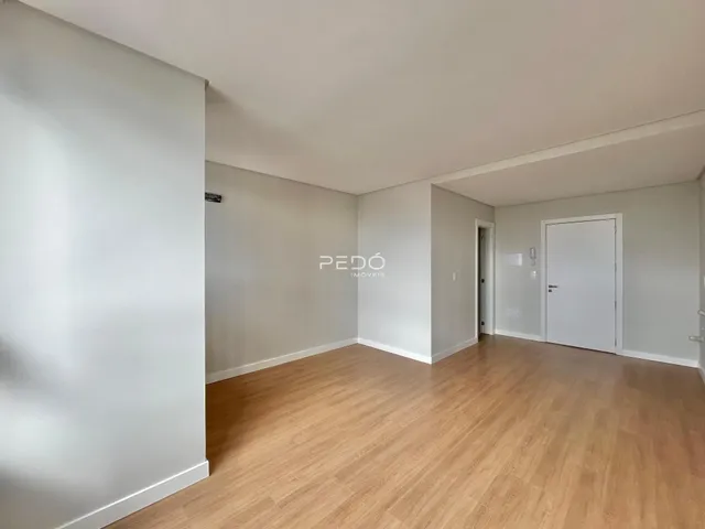 Ambiente interno com piso de madeira clara e paredes brancas.