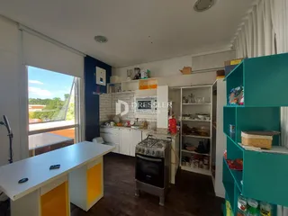 Vista interna de uma cozinha e sala de jantar com janela para o exterior.