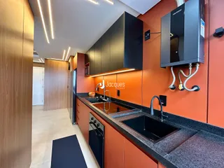Vista da cozinha moderna com armários laranja e bancadas escuras.