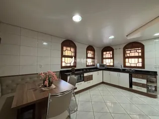 Interior de uma sala com janelas de madeira e armários de cozinha.