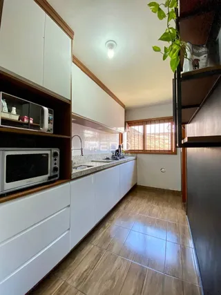 Foto de uma cozinha com armários brancos e piso de cerâmica.