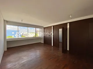 Sala de estar com piso de madeira e grande janela com vista.