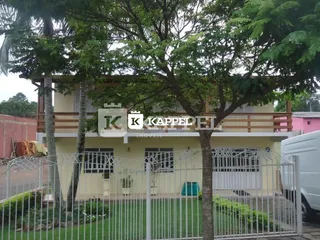 Fachada de uma residência com cerca e vegetação ao redor.