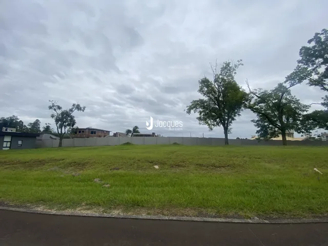 Vista externa de um terreno com gramado e árvores ao fundo.