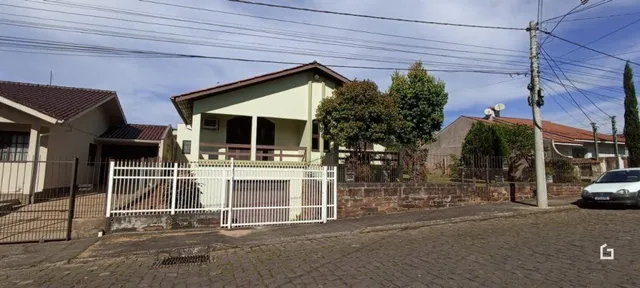 Fachada de uma residência em Lajeado, Brasil, com cerca e vegetação ao redor.