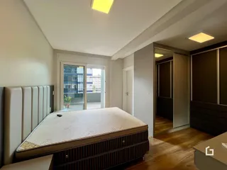 Quarto com cama e porta de vidro abrindo para a área externa.
