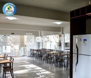 Ambiente interno com mesas e cadeiras em um espaço amplo.