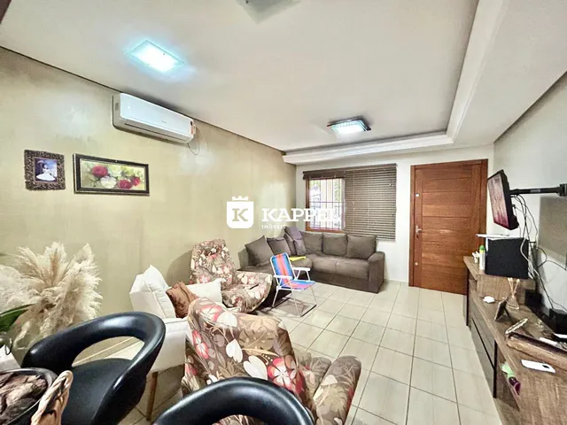 Sala de estar com sofá e poltronas em um ambiente claro com piso de cerâmica.