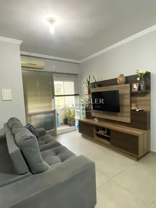 Sala de estar com sofá cinza e rack de TV em um imóvel no Brasil.