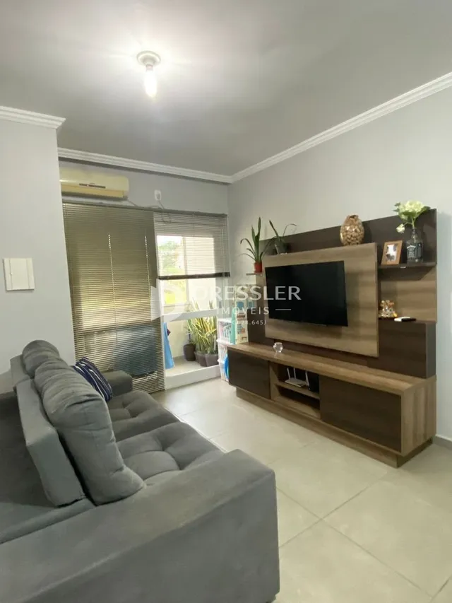 Sala de estar com sofá cinza e rack de TV em um imóvel no Brasil.
