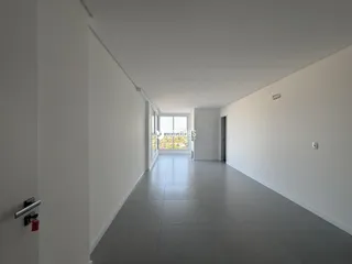 Corredor interno de uma residência com paredes brancas e piso cinza.