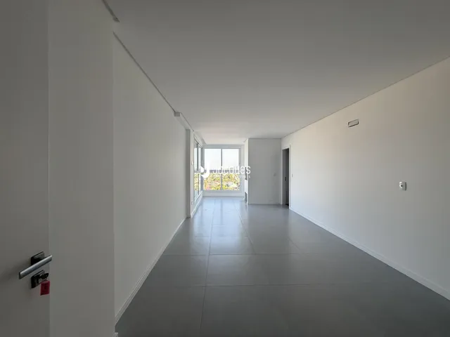 Corredor interno de uma residência com paredes brancas e piso cinza.