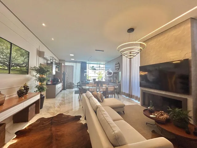 Uma sala de estar moderna com grandes janelas e lareira em um imóvel no Brasil.