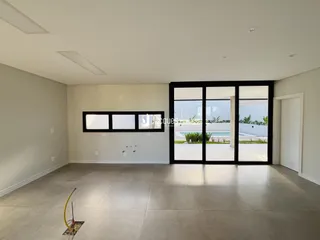 Ambiente interno de uma sala ampla com grandes portas de vidro que dão para o exterior.