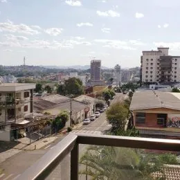 Vista externa de um bairro residencial em Lajeado, com edifícios ao fundo sob um céu parcialmente nublado.