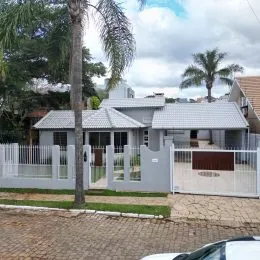 Foto da fachada de uma residência em Lajeado, Brasil, com cerca e jardim na frente.