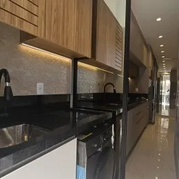 Vista interna da cozinha com armários de madeira e bancadas escuras.