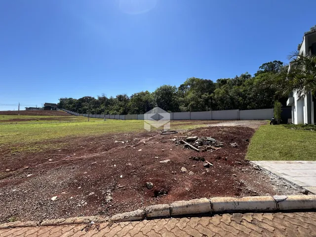Vista externa de um terreno com vegetação e cerca no fundo.
