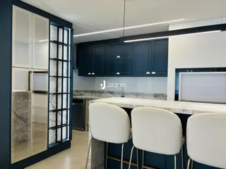 Vista interna de uma cozinha moderna com armários azul escuro e ilha de refeições.