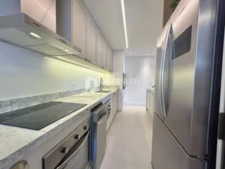 Vista da cozinha moderna com armários brancos e bancadas claras.