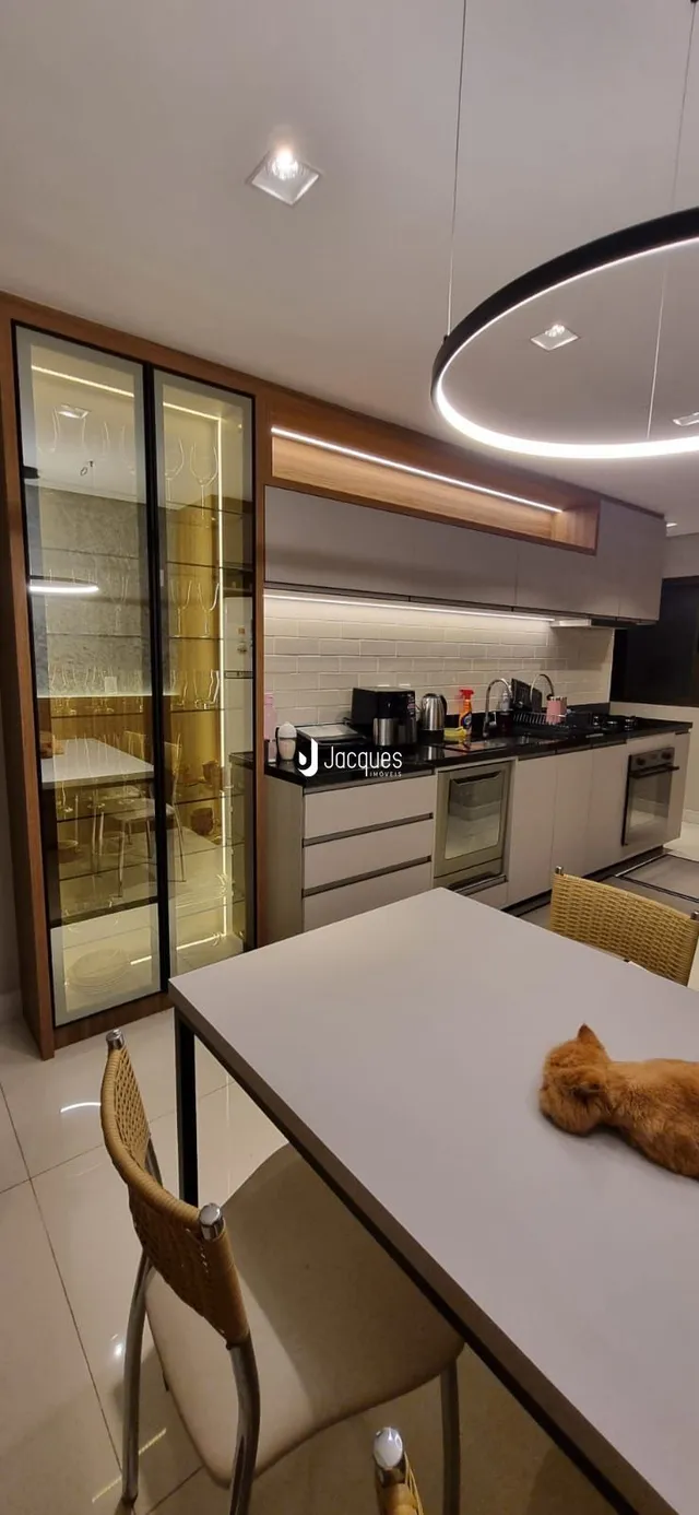 Cozinha moderna com armários brancos e bancadas escuras.