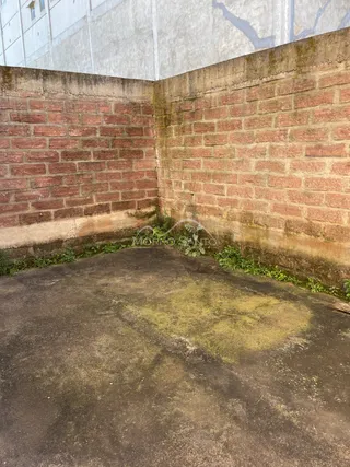 Parede de tijolos vermelhos com base de concreto no exterior da propriedade.