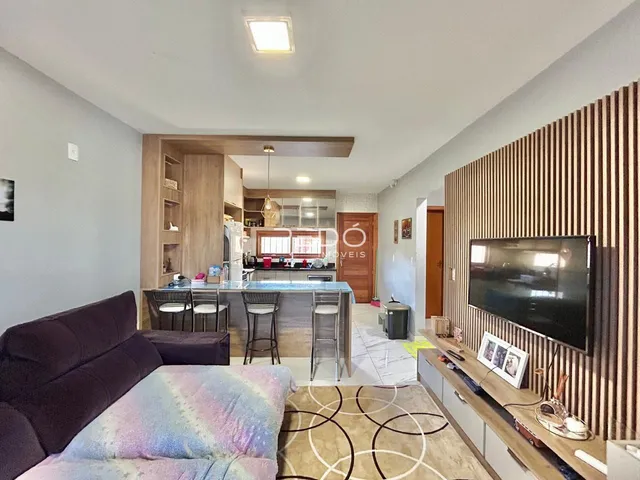 Sala de estar com cozinha aberta e parede de destaque em imóvel no Brasil.