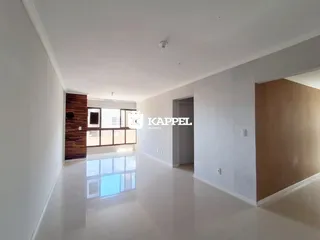 Sala ampla com piso claro e parede de madeira em um imóvel em Lajeado.