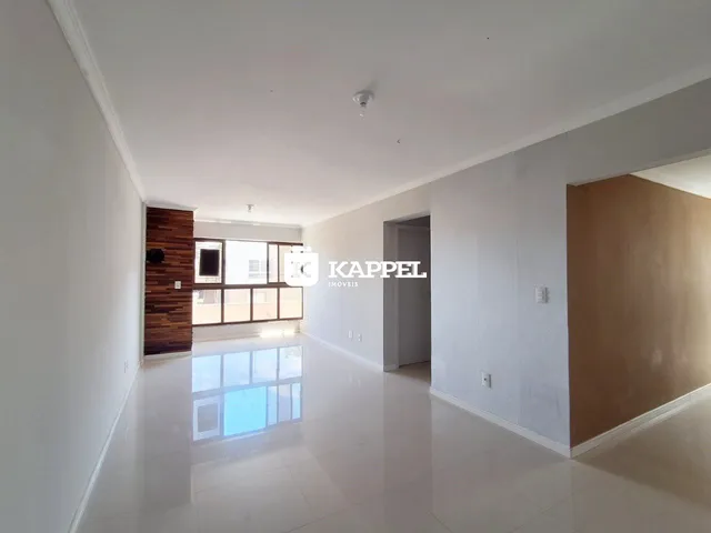 Sala ampla com piso claro e parede de madeira em um imóvel em Lajeado.