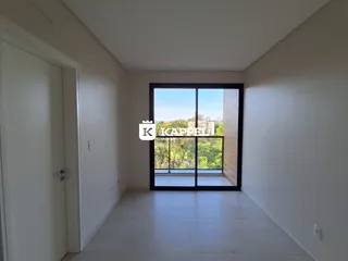 Hall de entrada com porta e grande janela de vidro que oferece vista para a vegetação externa.