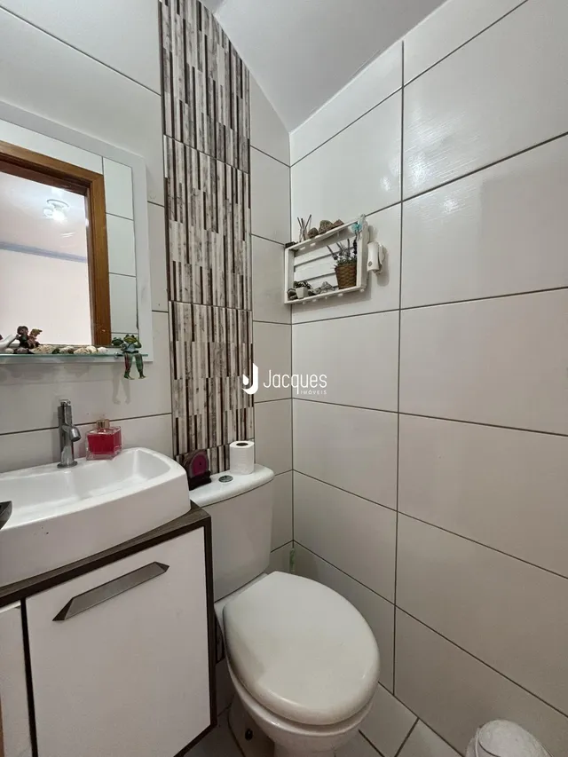 Um banheiro moderno com azulejos brancos e detalhes em madeira.