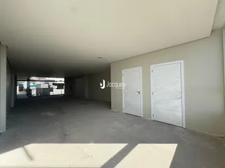 Vista interna de um espaço amplo com piso de concreto e portas brancas.