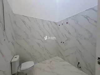 Interior de um banheiro com revestimento de mármore branco nas paredes.