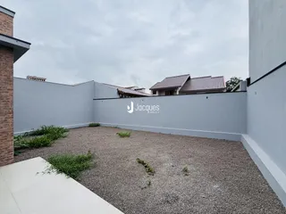 Área externa com piso de cascalho e muro branco.