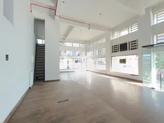 Corredor interno de um imóvel com piso de cerâmica e grandes janelas.