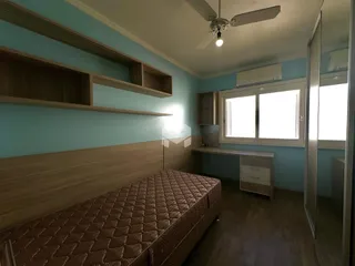 Quarto com cabeceira de madeira e paredes azul claro.