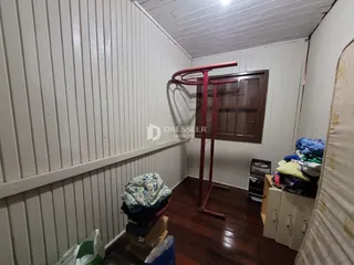 Interior de um cômodo com paredes brancas e piso de madeira escura.