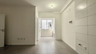 Hall de entrada com piso claro e paredes brancas em uma residência.