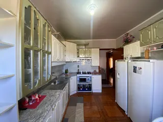 Vista da cozinha com armários brancos e bancadas de mármore.