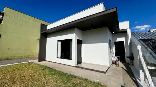 Fachada moderna de uma residência em Lajeado, Brasil, com paredes brancas e detalhes escuros.