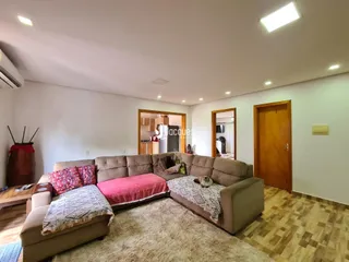 Sala de estar com sofá grande e piso de madeira em um imóvel no Brasil.