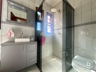 Foto interna de um banheiro com revestimento cerâmico e box de vidro.
