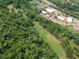 Vista aérea de uma área verde com construções rurais ao fundo.