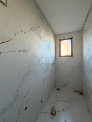 Corredor interno com paredes revestidas em mármore branco.