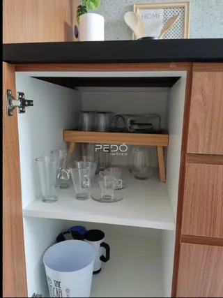 Armário de madeira com prateleiras exibindo louças e utensílios de cozinha.