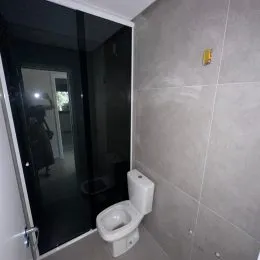 Foto interna de um banheiro com revestimento de azulejos brancos.