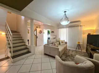 Uma sala de estar com escadaria e piso de cerâmica.