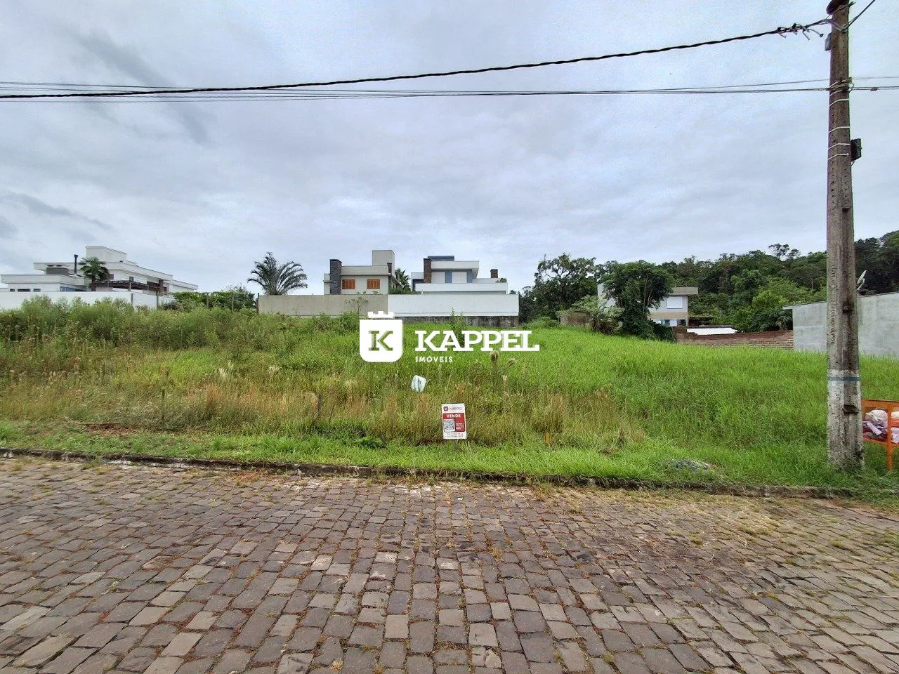 Vista externa da propriedade mostrando o terreno e as construções ao fundo.
